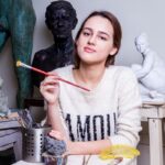 woman leaning on table and holding paint brush